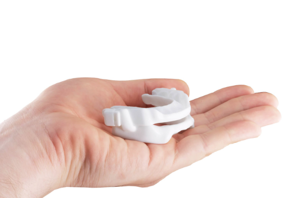 An extended hand holding a snoring breathing device that will help to mitigate noise during sleep